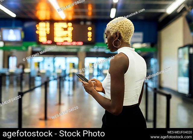 Young woman using smart phone while standing at subway station