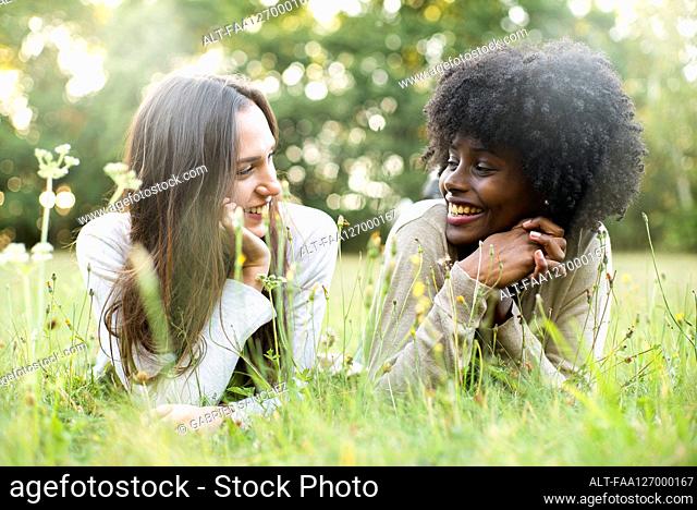 Portrait of smiling young female friends lying in park