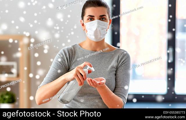 close up of woman in mask applying hand sanitizer