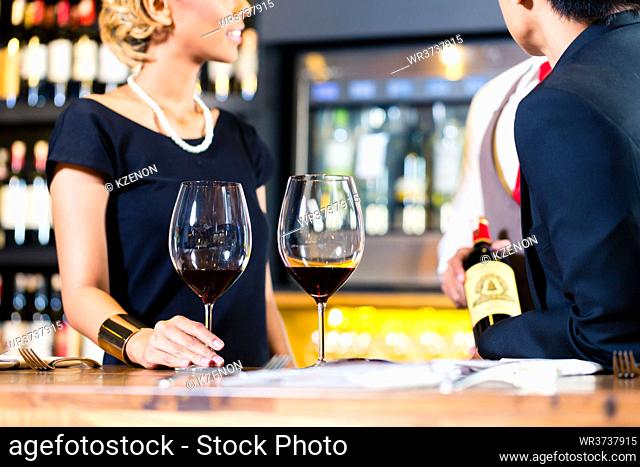 Asian couple tasting red wine in wine shope
