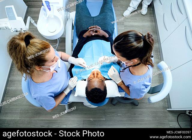 Female dentist and assistent attending patient in medical practice