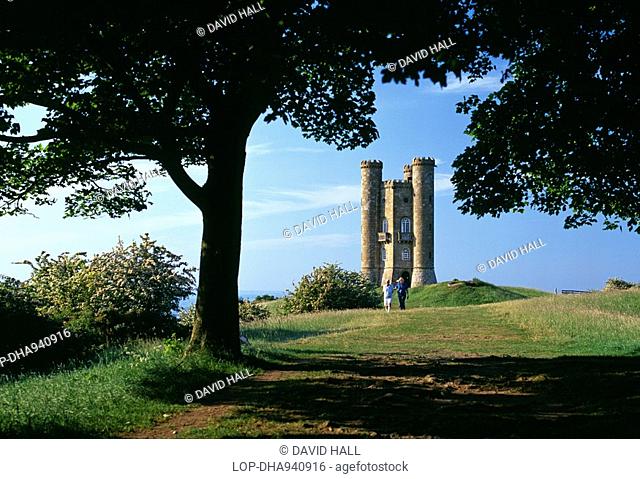 A couple walking away from Broadway Tower, an 18th century folly tower inspired by Capability Brown. The tower is situated in an Area of Outstanding Natural...