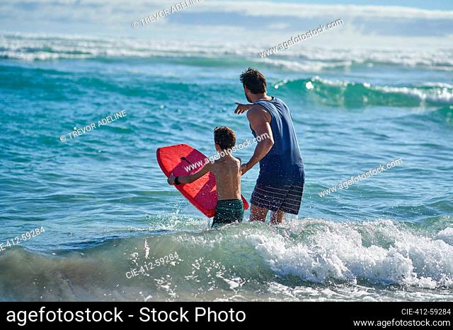 Father and son with body board watching ocean waves