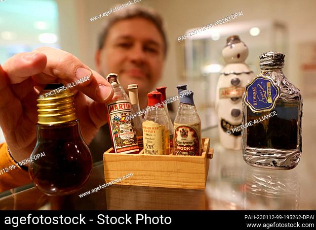 12 January 2023, Thuringia, Nordhausen: Thomas Müller, manager of the traditional Nordhausen distillery, shows the smallest miniature bottles in the exhibition