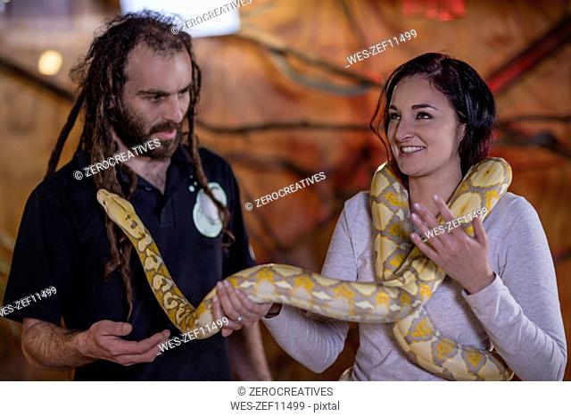 Animal attendant handing over albino python snake to woman
