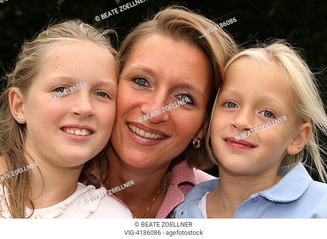 Three - Portrait : smiling mother with her two daughters at school age cheek - , Hamburg, Germany, 19/09/2005
