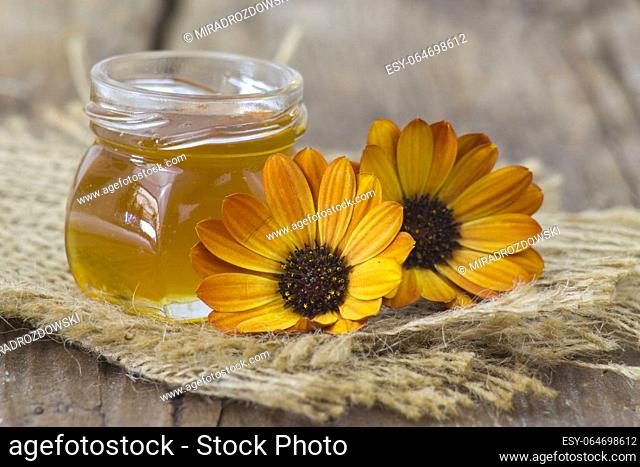 honey and calendula flowers on wooden background