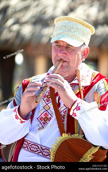 08/29/2020 Belarus, Lyaskovichi. Celebration in the city. An elderly Slavic man in national dress plays the pipe