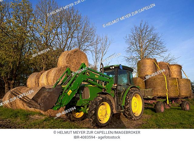 Tractor with round straw bales on a field and on a trailer, Othenstorf, Mecklenburg-Western Pomerania, Germany