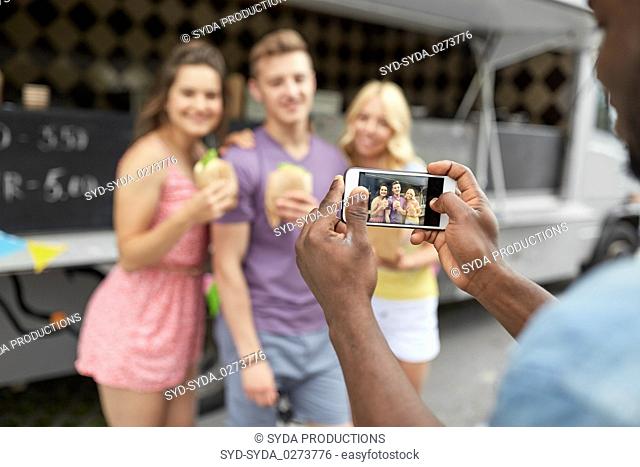 man taking picture of friends eating at food truck