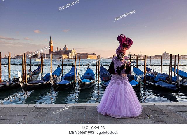 Venice, Veneto, Italy, A traditional mask at Venice Carnival with St George island and some gondolas in background at sunset