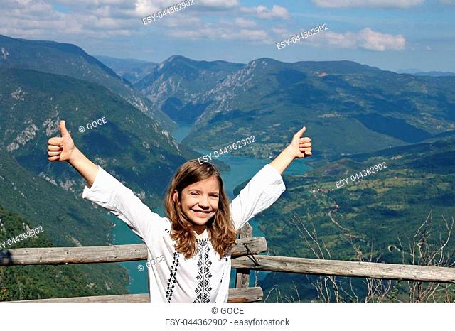 happy little girl with thumbs up on mountain top