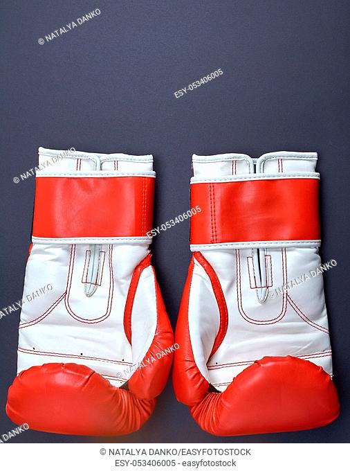 pair of red-white leather boxing gloves on a black background, copy space