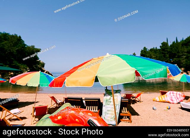 Bright colored umbrellas on the royal beach in Przno against the backdrop of the sea and green trees. High quality photo