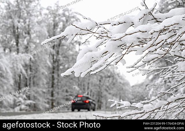 04 December 2023, Baden-Württemberg, Bebenhausen: Cars drive through a snow-covered forest on a road near Bebenhausen. Photo: Bernd Weißbrod/dpa