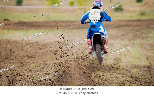 Motocross racer start riding his dirt Cross MX bike, telephoto