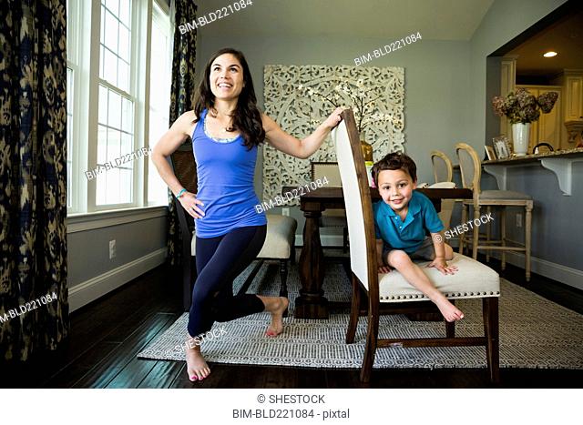 Mother stretching with son in dining room