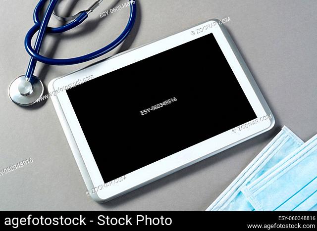 High angle shot of tablet and medical items on gray surface