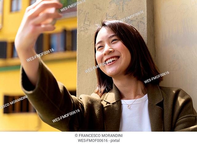 Italy, Florence, happy young woman taking a selfie in the city