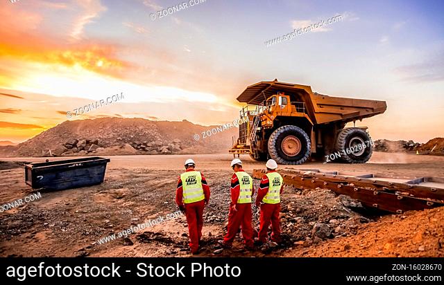 Rustenburg, South Africa, October 15, 2012, Large Dump Trucks transporting Platinum ore for processing with mining safety inspectors in the foreground