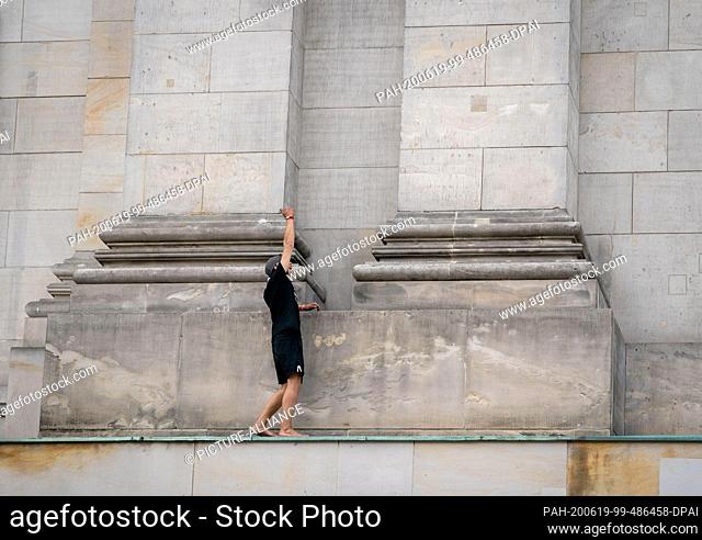 19 June 2020, Berlin: A man stands on a ledge of the Reichstag building. The person had climbed up the facade of the building and shouted slogans