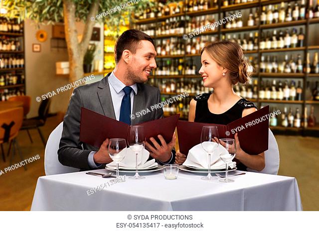 happy couple with menus at restaurant or wine bar