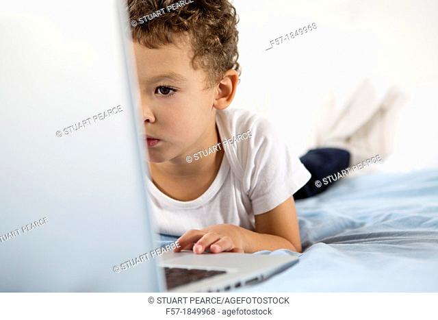 Four year old boy playing games on a laptop