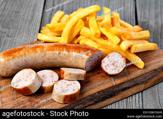 German sausage and potato fry on a wooden
