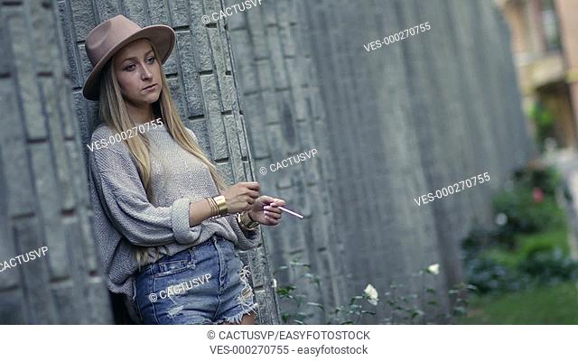 Woman smoking and leaning on the loft brick wall