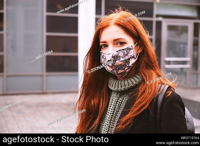 young woman wearing self-made everyday cloth face mask outdoors in city - new normal covid-19 corona virus pandemic concept - real people lifestyle in winter