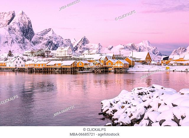 The colors of dawn frames the fishermen houses surrounded by snowy peaks Sakrisøy Reine Nordland Lofoten Islands Norway Europe