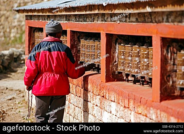 A Nepalese man turns prayer wheels in Namche Bazaar, in the Everest region of Nepal. In the Tibetan Buddhist tradition, turning the prayer wheels is equivalent...