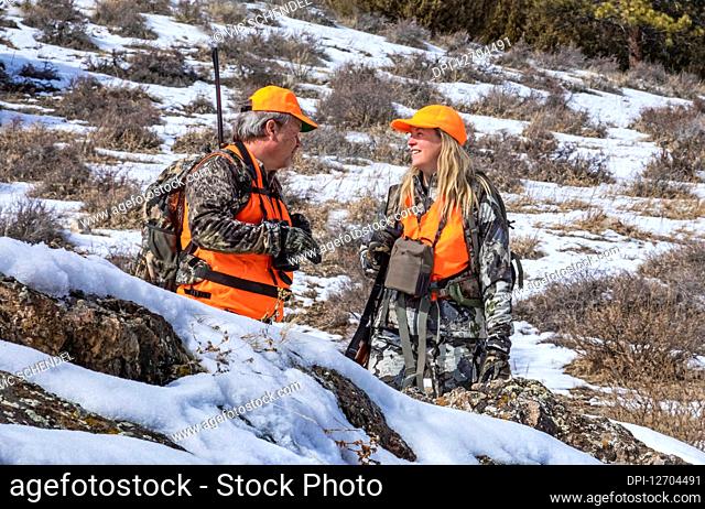 Hunters with camouflage clothing, orange vests and rifles talking Denver, Colorado, United States of America