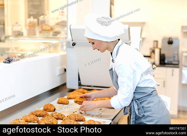 Confectioner woman baking pastry roles, chocolate bread, and croissants