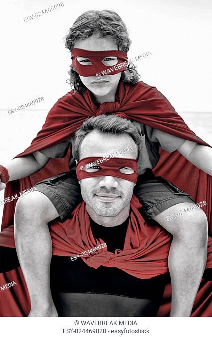 Confident father in superhero costume carrying son on shoulder