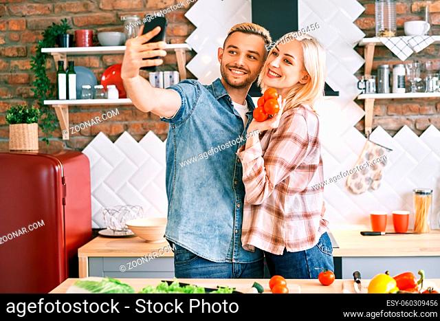 Young happy couple take selfie at their kitchen at home