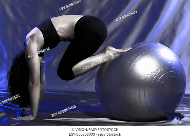 young woman exercising swiss ball studio