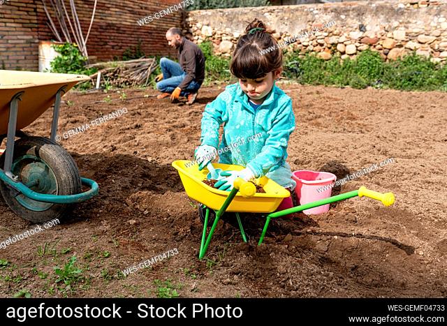 Playful girl gardening with father in backyard
