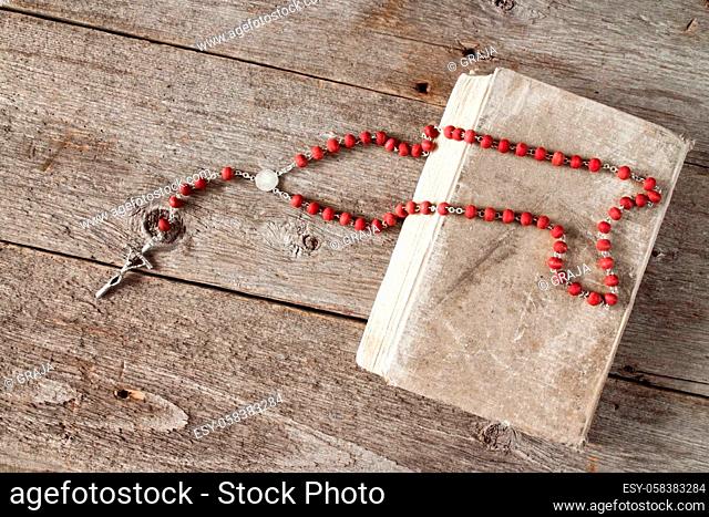 The rosary and old book on wooden background.Top view