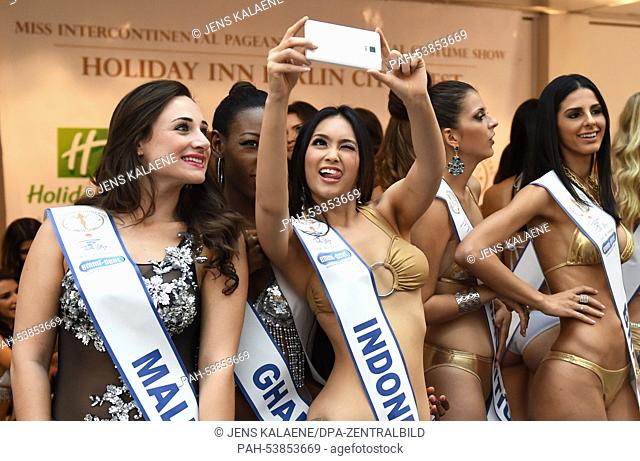 Contestants take selfies in their sashes at a photo shoot for the Miss Intercontinental Contest at the hotel Holiday Inn Berlin City West in Berlin,  Germany