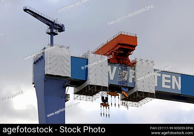 PRODUCTION - 07 November 2023, Mecklenburg-Western Pomerania, Rostock-Warnemünde: Scaffolding and cladding can be seen on the Warnowwerft gantry crane