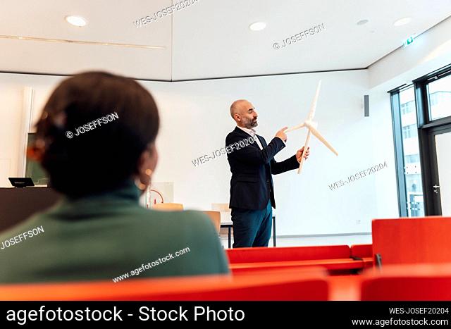 Mature businessman giving presentation and having discussion over wind turbine with businesswoman