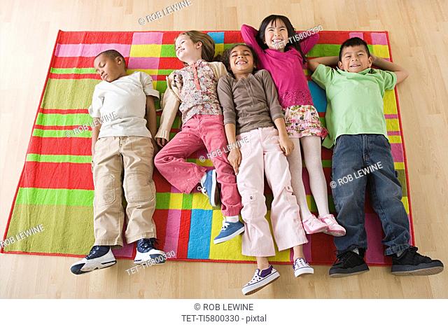 Children 6-7 lying on blanket in classroom