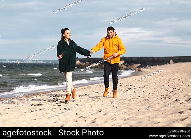 couple running along autumn beach