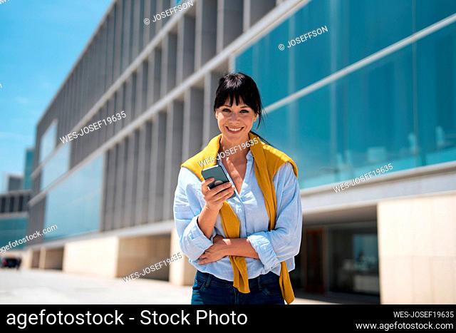 Smiling mature businesswoman holding mobile phone