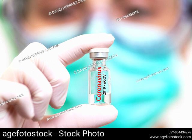 A doctor in medical gloves and mask holding an ampula with vaccine. Close up shot. Coronavirus, epidemic and medicine concept