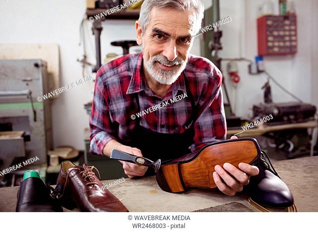 Cobbler smiling and holding a hammer and a shoe