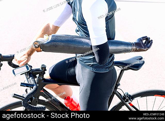 Close-up of male athlete holding artificial hand while riding bicycle on road