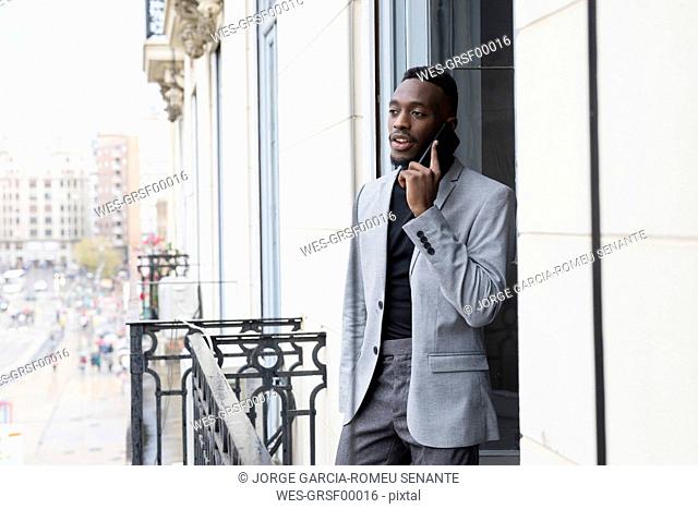 Portrait of young businessman on the phone standing on balcony