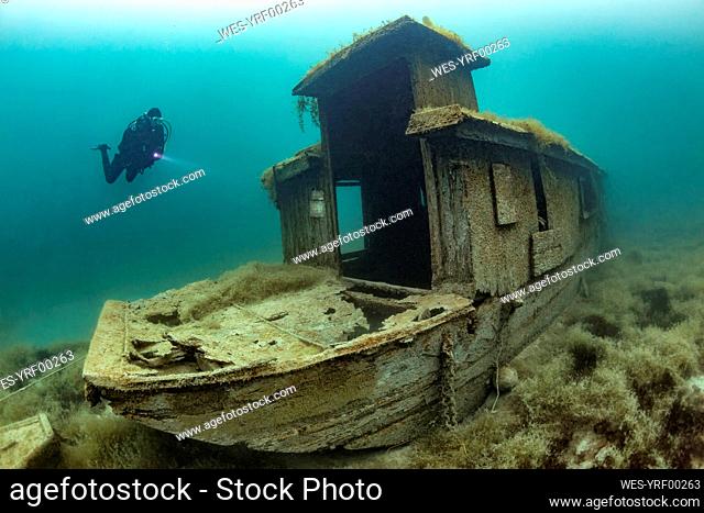 Scuba diver swimming toward shipwreck sunken in Lake Atter